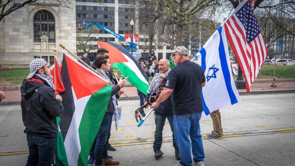 Man holding a US and Israeli flag talking with Pro palestine protestors